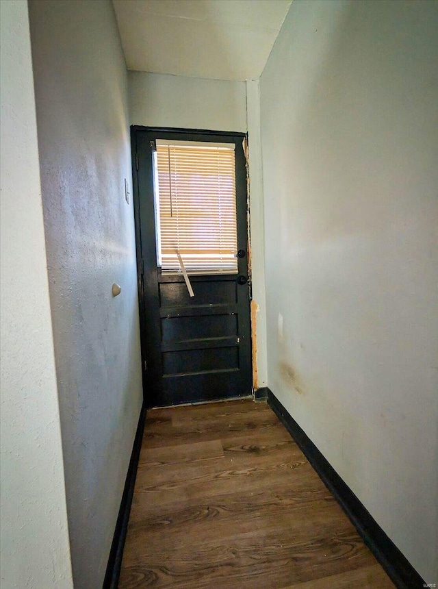 doorway with dark wood-style floors and baseboards