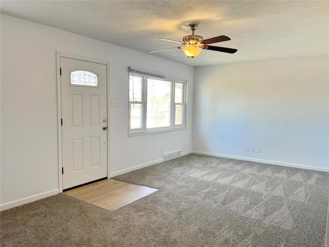 carpeted foyer entrance with baseboards, visible vents, and ceiling fan