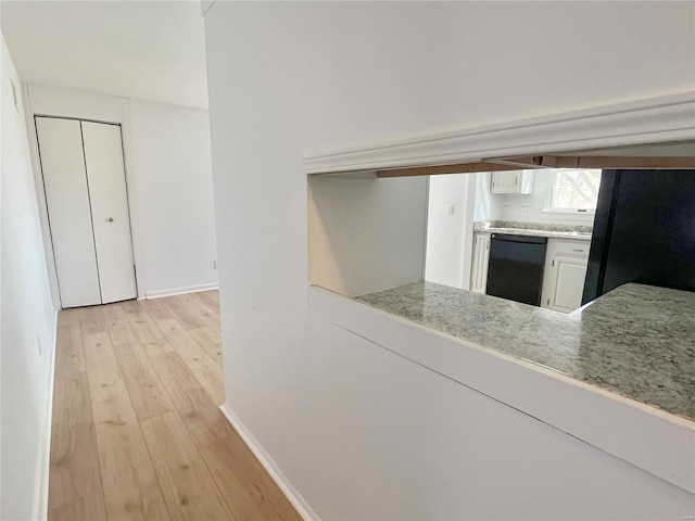 kitchen featuring baseboards, black appliances, light countertops, white cabinetry, and light wood-type flooring