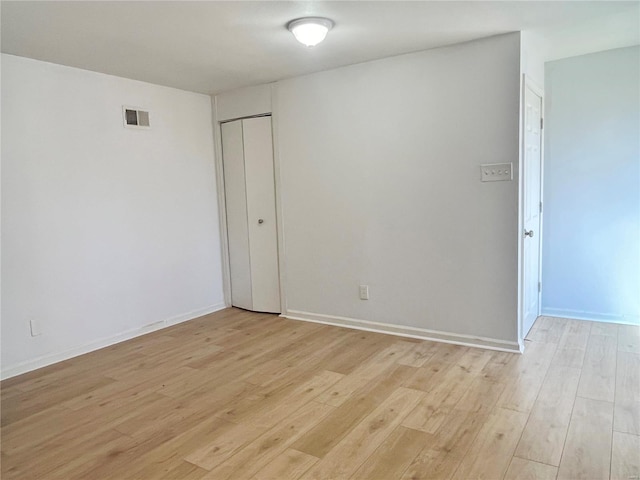 empty room featuring visible vents, light wood-style flooring, and baseboards