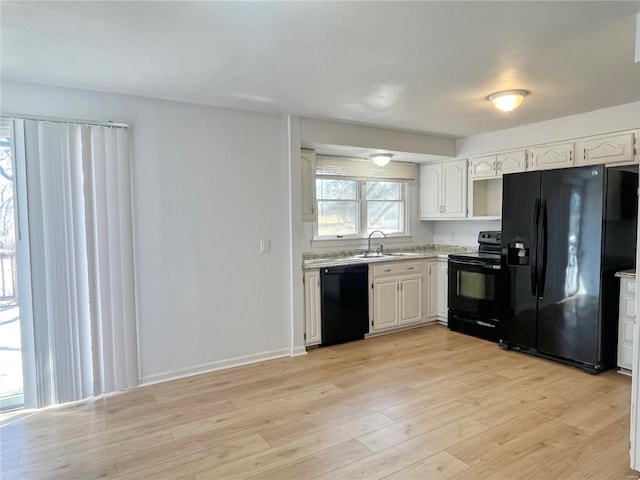 kitchen featuring light wood-style flooring, a sink, black appliances, light countertops, and white cabinetry