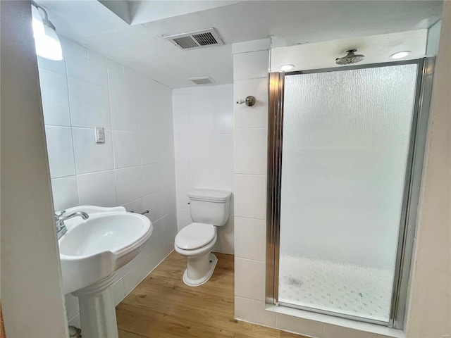 full bathroom with wood finished floors, visible vents, a shower stall, tile walls, and toilet