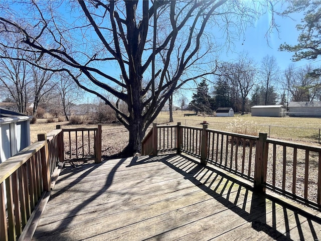 wooden deck featuring a storage unit, an outdoor structure, and fence