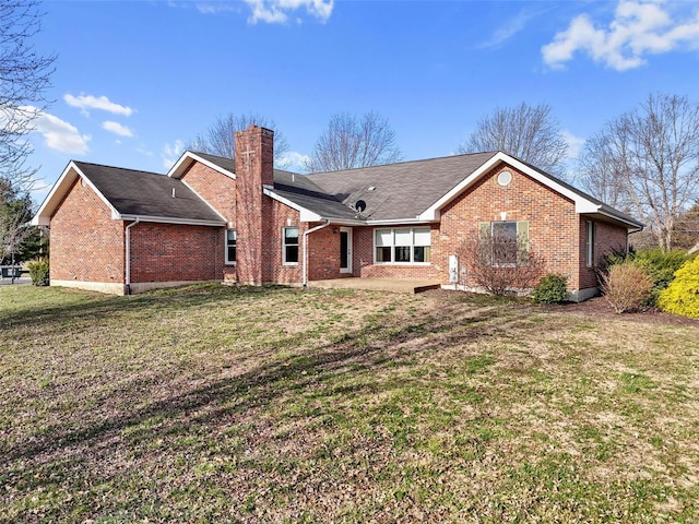 rear view of property with brick siding, a chimney, and a yard