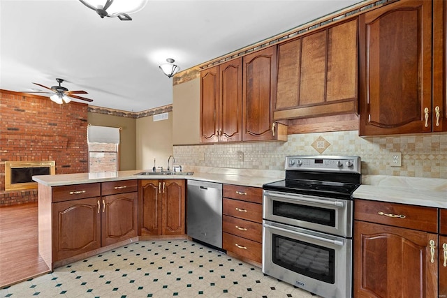 kitchen with a ceiling fan, a peninsula, a sink, stainless steel appliances, and light countertops