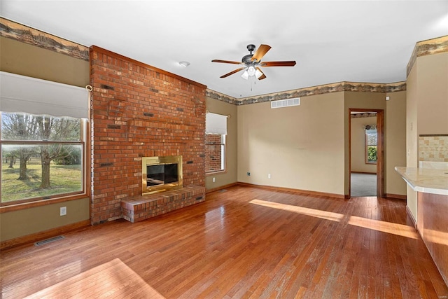 unfurnished living room with visible vents, a fireplace, ceiling fan, and hardwood / wood-style floors