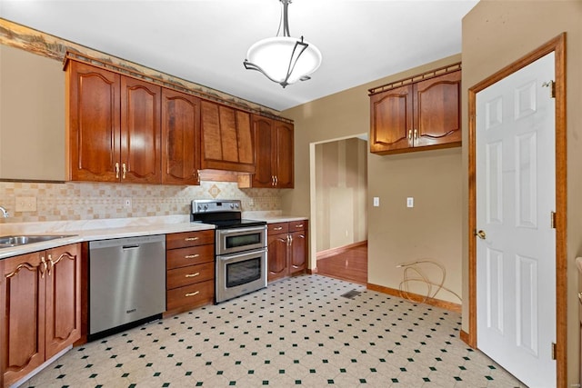 kitchen with brown cabinetry, appliances with stainless steel finishes, light countertops, and a sink