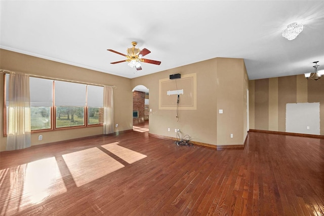 interior space with arched walkways, ceiling fan with notable chandelier, baseboards, and hardwood / wood-style floors