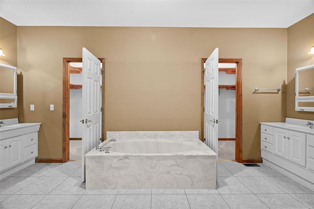 bathroom with tile patterned floors, baseboards, a bath, and vanity