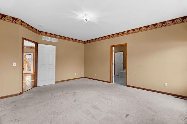 empty room featuring visible vents, light carpet, and baseboards