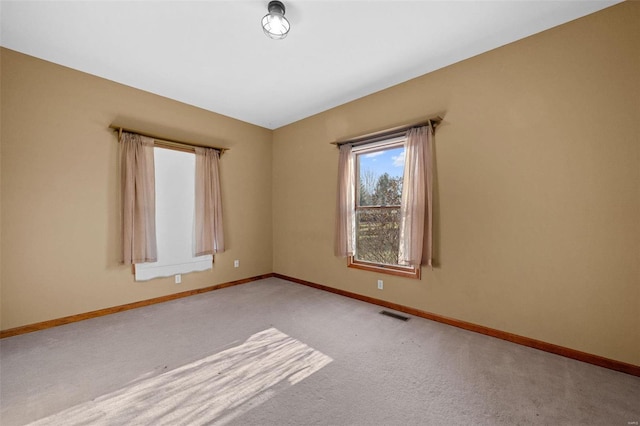 carpeted spare room with visible vents and baseboards