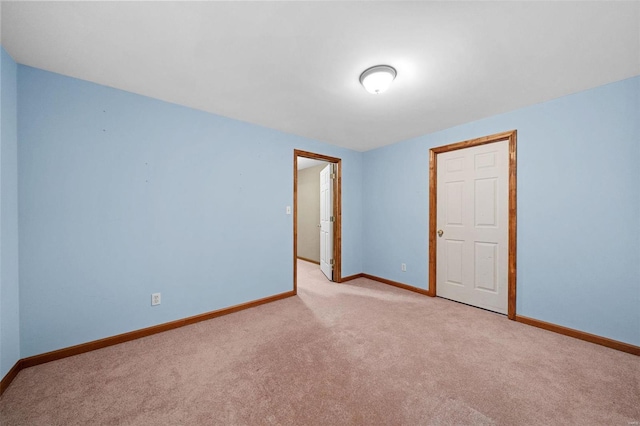 spare room featuring light carpet and baseboards