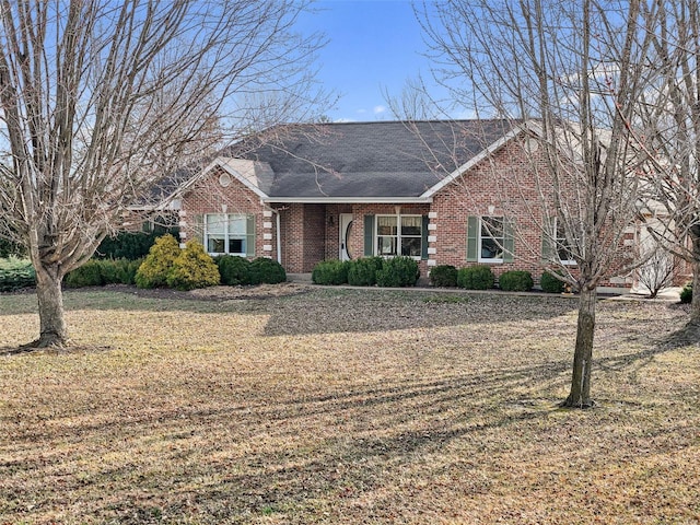 ranch-style home with a front lawn, brick siding, and roof with shingles