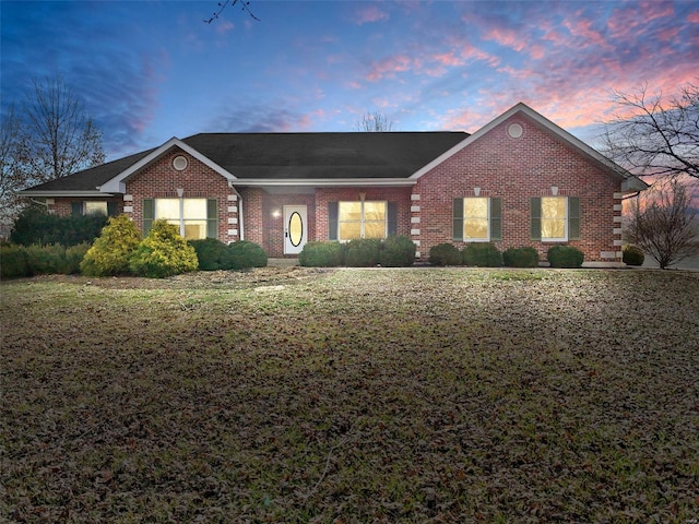 view of front facade featuring brick siding and a lawn