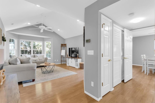 living area with ceiling fan, baseboards, lofted ceiling, and light wood-style flooring