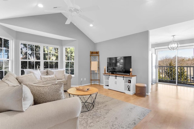 living area featuring light wood finished floors, baseboards, recessed lighting, ceiling fan with notable chandelier, and high vaulted ceiling