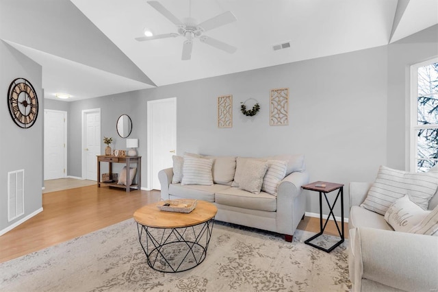 living area with visible vents, lofted ceiling, baseboards, and wood finished floors