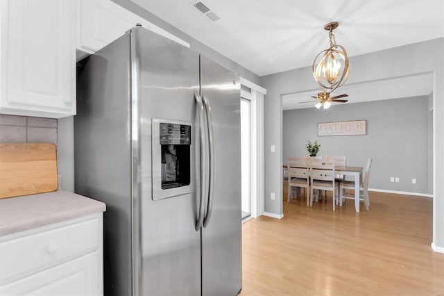 kitchen featuring visible vents, light countertops, white cabinets, light wood-style floors, and stainless steel refrigerator with ice dispenser