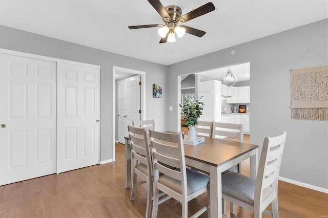 dining area featuring light wood-style flooring, a ceiling fan, and baseboards