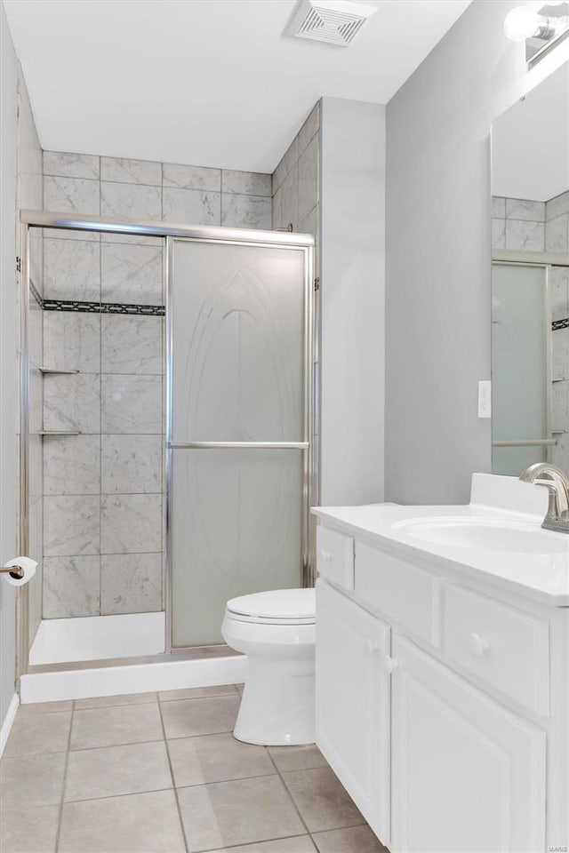 bathroom with vanity, visible vents, a stall shower, tile patterned flooring, and toilet