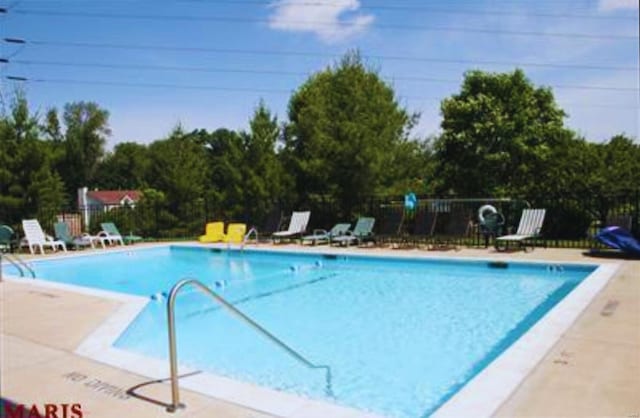 pool with a patio area and fence