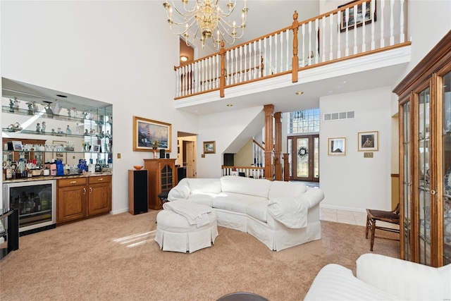 living area featuring visible vents, baseboards, decorative columns, a bar, and light colored carpet