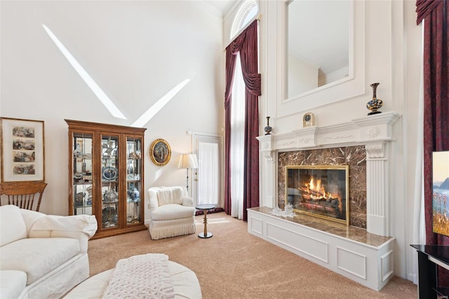 living room featuring a premium fireplace, light colored carpet, and a high ceiling