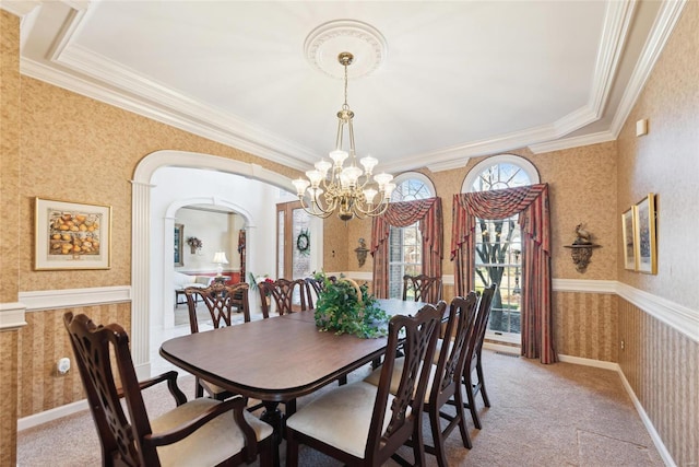 dining area featuring wallpapered walls, a wainscoted wall, light colored carpet, an inviting chandelier, and arched walkways