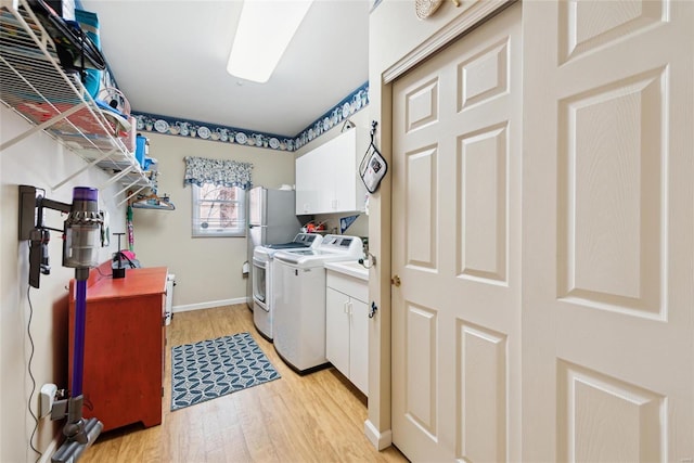 laundry room featuring washing machine and dryer, cabinet space, baseboards, and light wood-style flooring