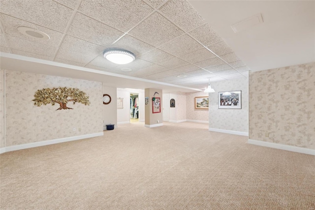 finished below grade area with carpet flooring, wallpapered walls, a paneled ceiling, and baseboards