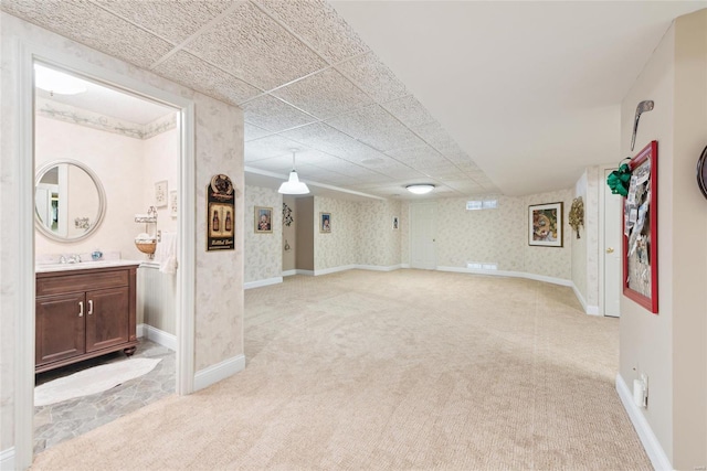 finished below grade area featuring baseboards, light colored carpet, and wallpapered walls