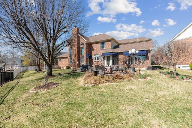 rear view of property with a yard, fence, brick siding, and a chimney