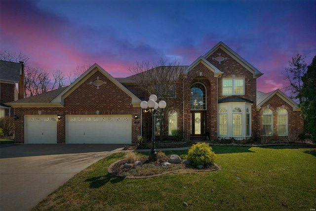 traditional-style home with brick siding, an attached garage, concrete driveway, and a yard