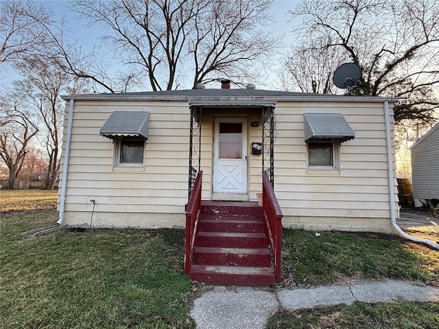 bungalow featuring a chimney and a front lawn