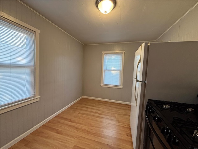 kitchen featuring crown molding, light wood-style flooring, gas range oven, and baseboards