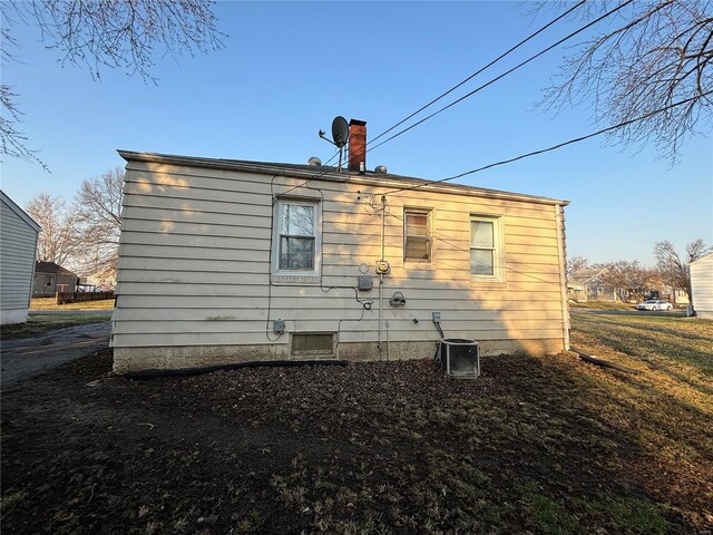 rear view of house with central AC and a chimney