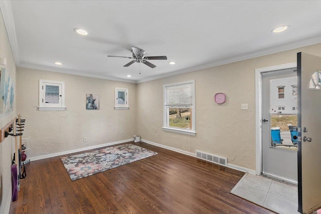 interior space with visible vents, ornamental molding, baseboards, and wood finished floors