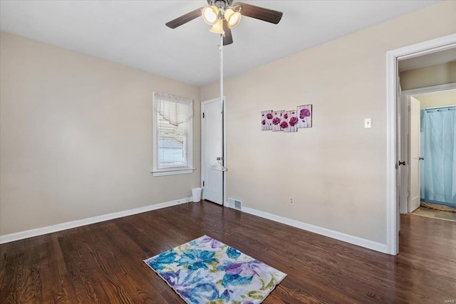 empty room featuring wood finished floors, baseboards, visible vents, and ceiling fan