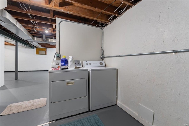 laundry area featuring washing machine and dryer, laundry area, and a textured wall