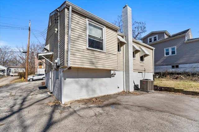 view of property exterior featuring central AC unit and a chimney