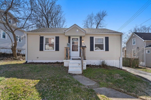 bungalow featuring a front yard, fence, and a shingled roof