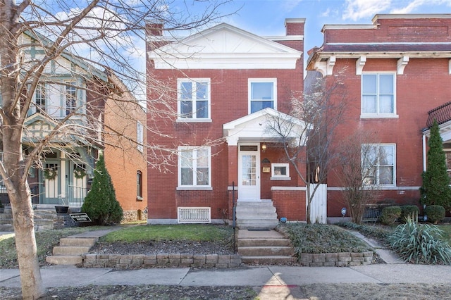 view of front facade featuring brick siding and a chimney