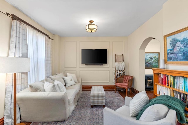 living area featuring a decorative wall, wood finished floors, and arched walkways