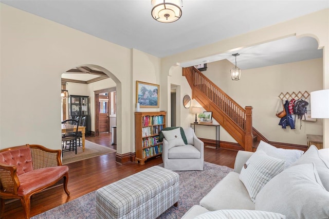 living room with arched walkways, stairway, baseboards, and wood finished floors