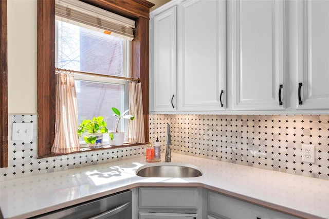 kitchen with a sink, backsplash, stainless steel dishwasher, and light countertops