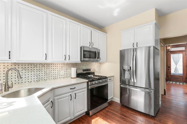 kitchen with a sink, backsplash, white cabinetry, appliances with stainless steel finishes, and light countertops