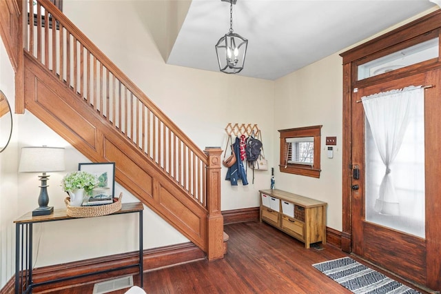 foyer featuring visible vents, dark wood-type flooring, baseboards, stairway, and a notable chandelier