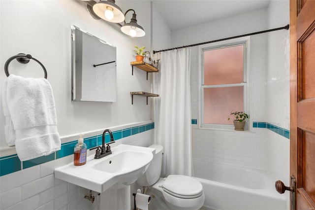 full bathroom with tile walls, shower / tub combo, toilet, and a wainscoted wall