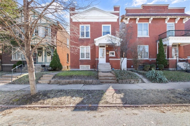 view of front of home with brick siding and a chimney