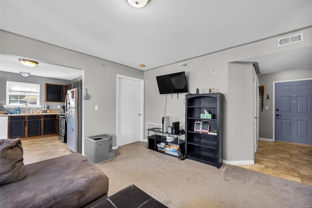 living area with baseboards, visible vents, and light carpet